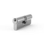 Shiny silver cylinder lock with a key partially inserted on the left, resting on a white surface.