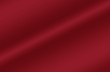 Close-up of deep red satin fabric with diagonal folds and soft sheen, conveying luxury and warmth.