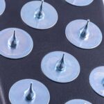 Close-up of round metal discs with central conical spikes on a dark surface