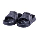 Pair of black slide sandals with metal spikes on the soles for traction.
