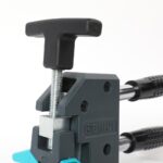 Close-up of a clamp-style crimping tool with a black T-shaped handle and a threaded screw assembly for adjusting tension.