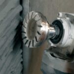 Close-up of a metal end-mill cutter with multiple teeth mounted on a machine spindle, cutting a metal workpiece